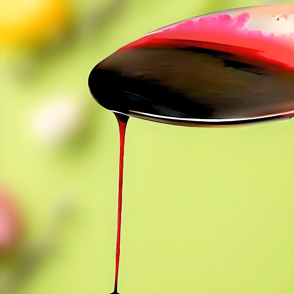 Dark fruit coulis poured from a spoon